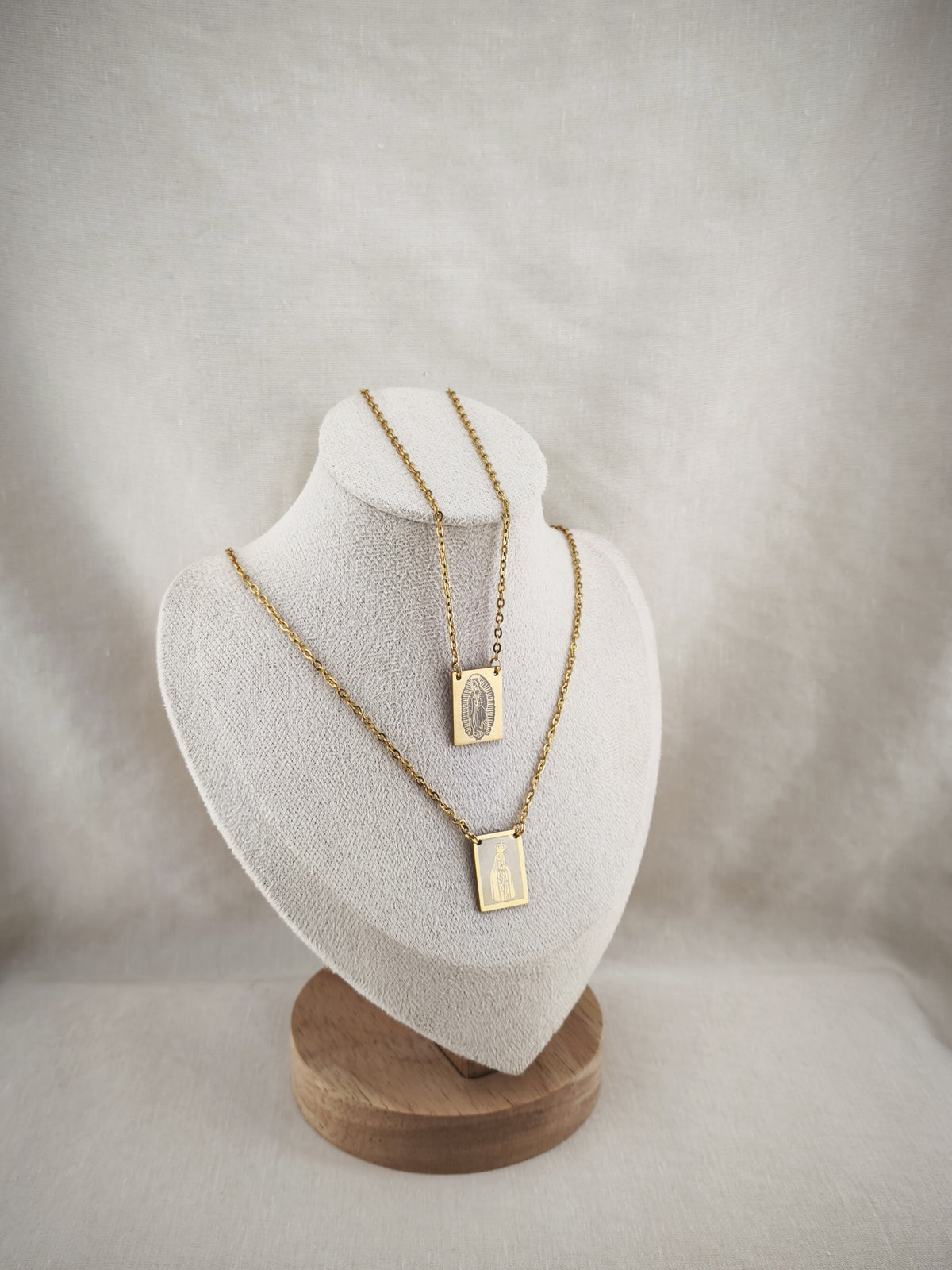 Colar Escapulário Além-Mar dourado, com medalhas de Nossa Senhora de Fátima e de Nossa Senhora de Guadalupe, apresentado em expositor.