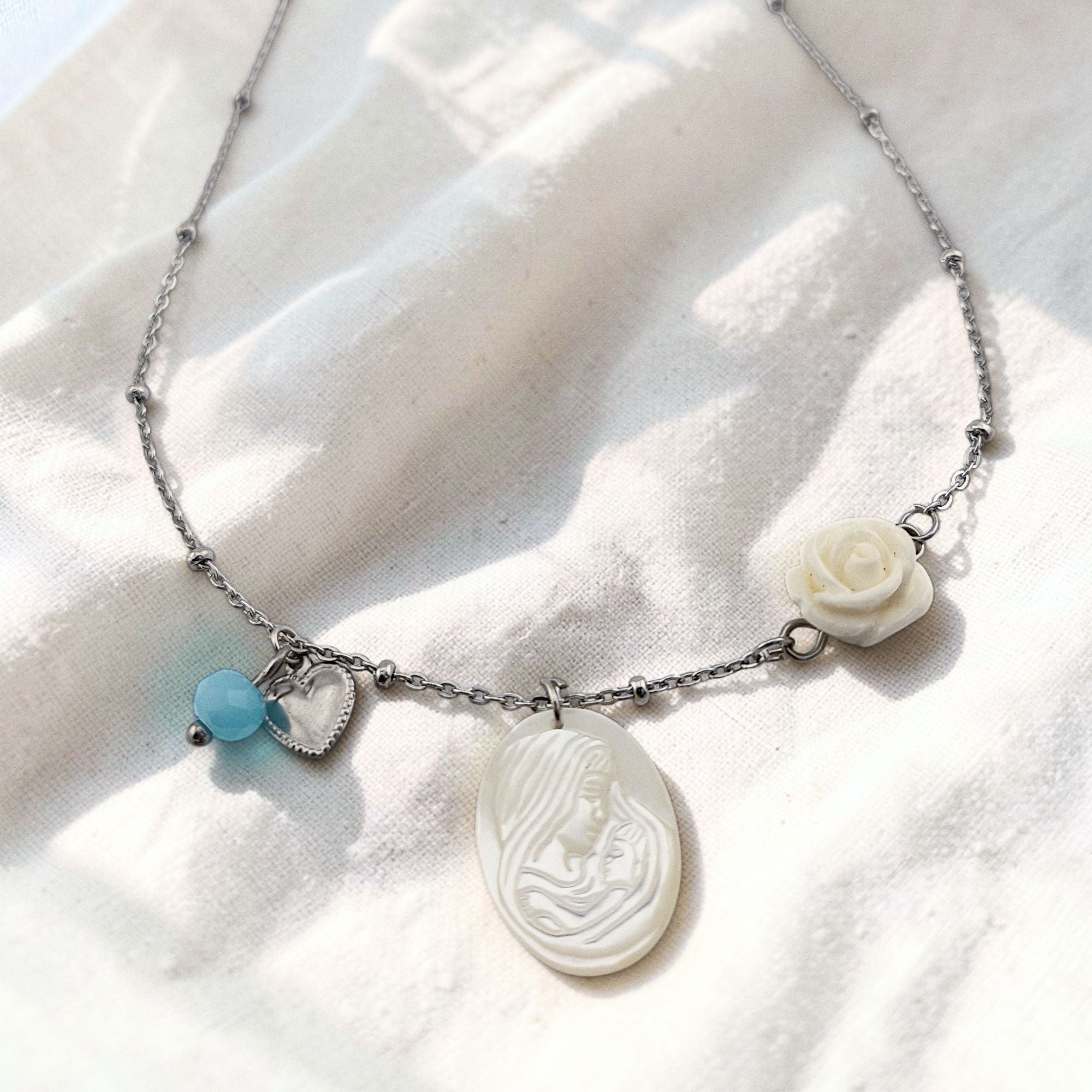 Colar gargantilha em aço inoxidável dourado com medalha em madre pérola N. S. do Carmo, cristal rosa, coração e rosa em resina. Coleção Religiosos | Joias de Fé