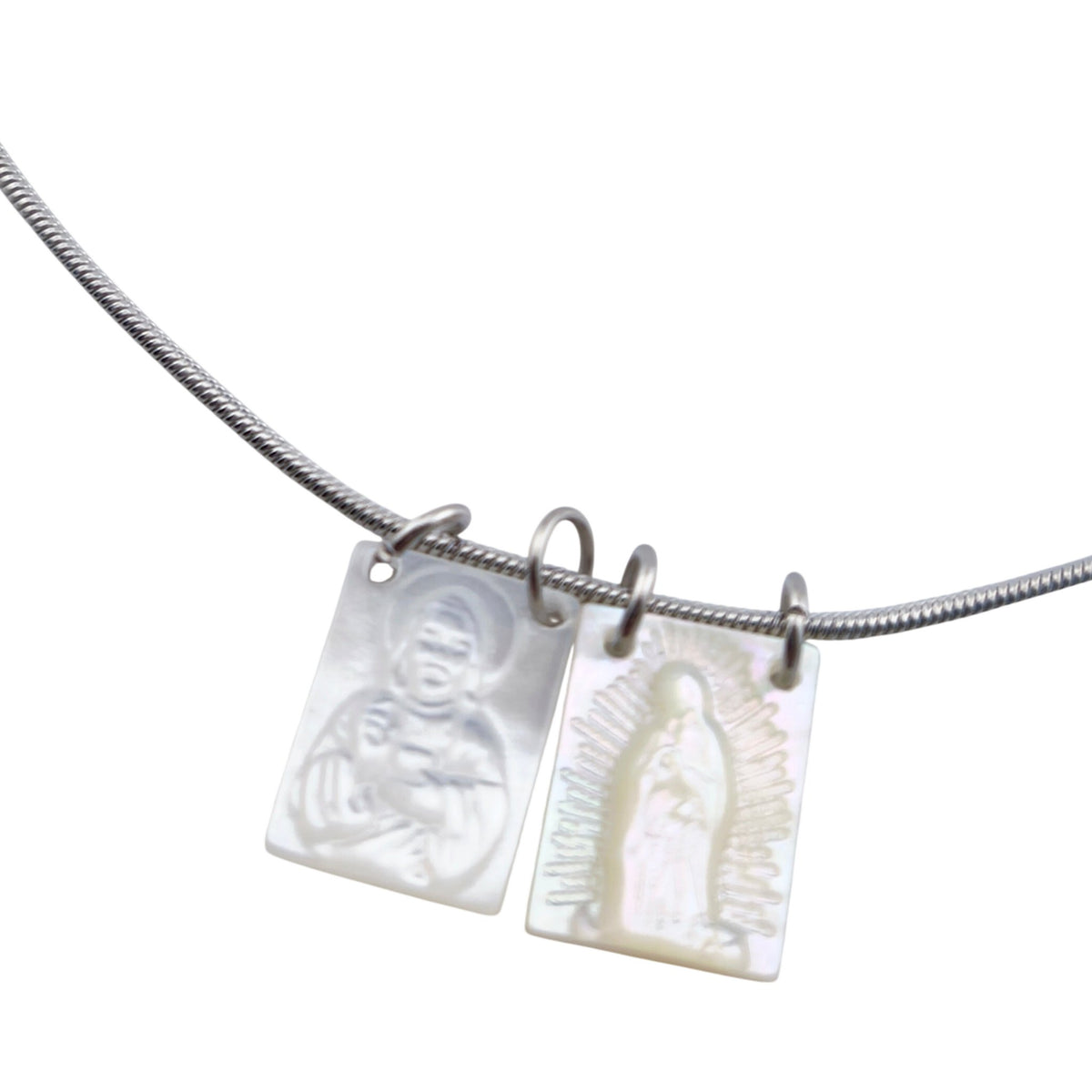 Colar Escapulário Amparo prateado, pormenor das medalhas, sobre fundo branco.