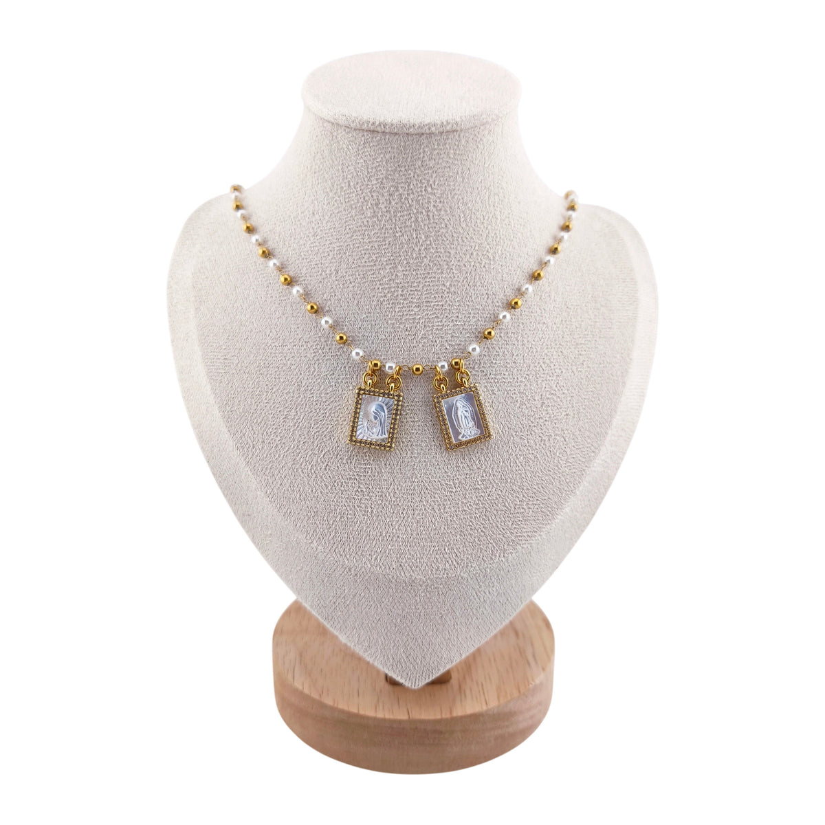 Colar Escapulário Luz Celestial dourado, com pérolas, apresentado em expositor.