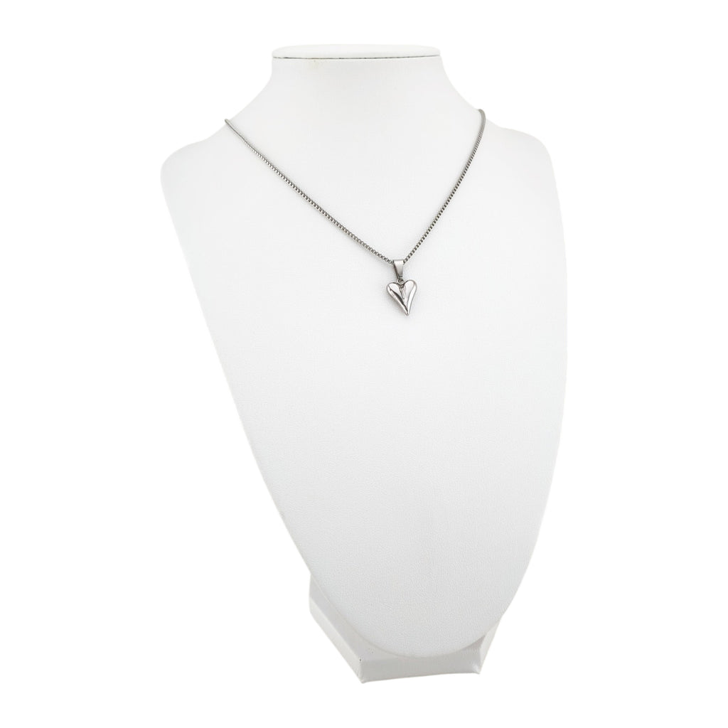 Fio Essência do Amor prateado apresentado em expositor branco, com corrente Veneziana e pendente coração em aço inoxidável.