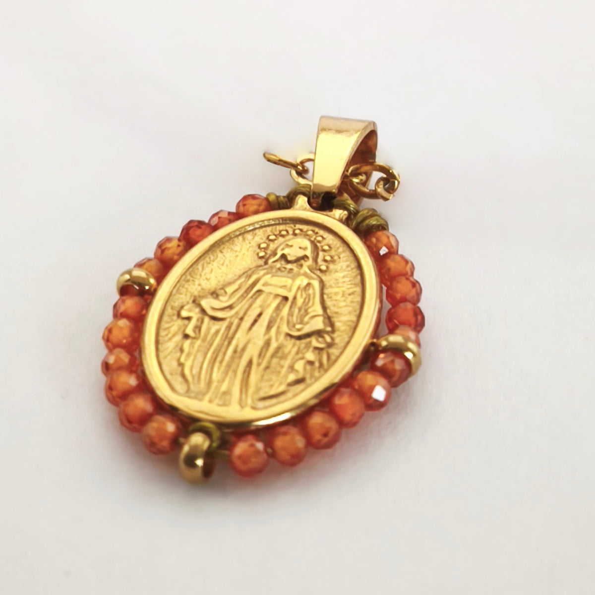 Pendente Orvalho dourado, com medalha de Nossa Senhora das Graças rodeada de contas laranja, em perspetiva.