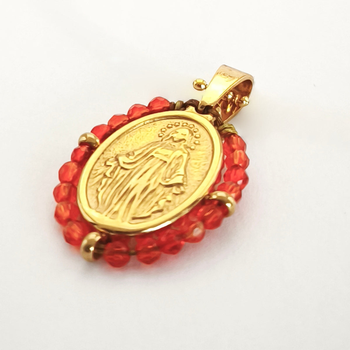 Pendente Orvalho dourado, com medalha de Nossa Senhora das Graças rodeada de contas laranja avermelhado, em perspetiva.