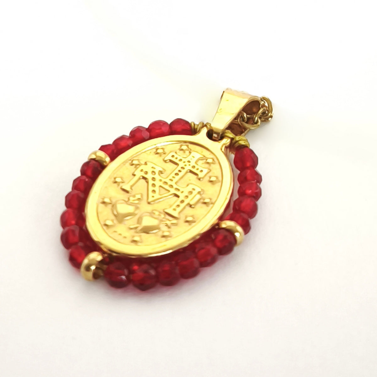Pendente Orvalho dourado, verso da medalha rodeada de contas vermelho escuro, com a letra M, a cruz, os dois corações e as doze estrelas.