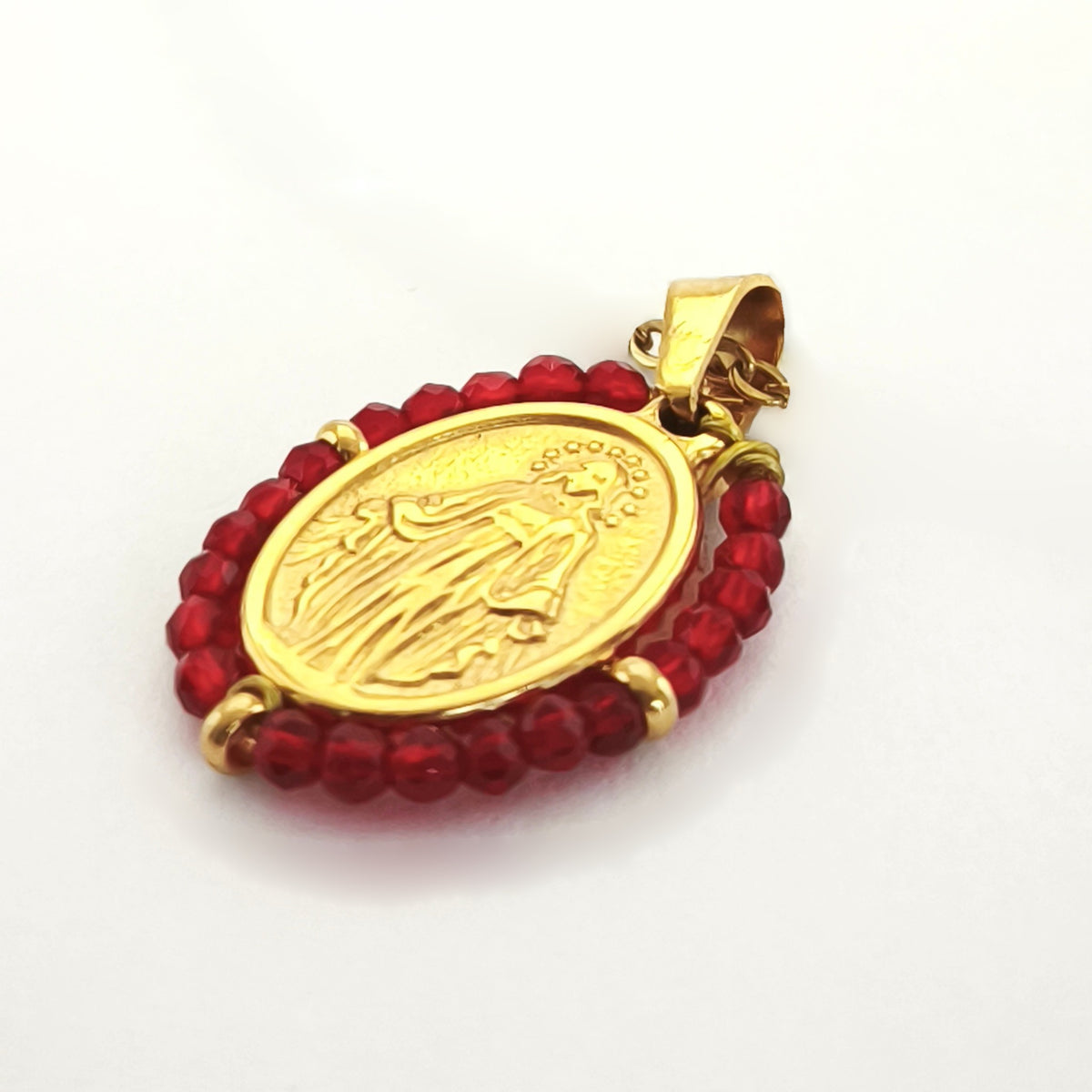 Pendente Orvalho dourado, com medalha de Nossa Senhora das Graças rodeada de contas vermelho escuro, em perspetiva.