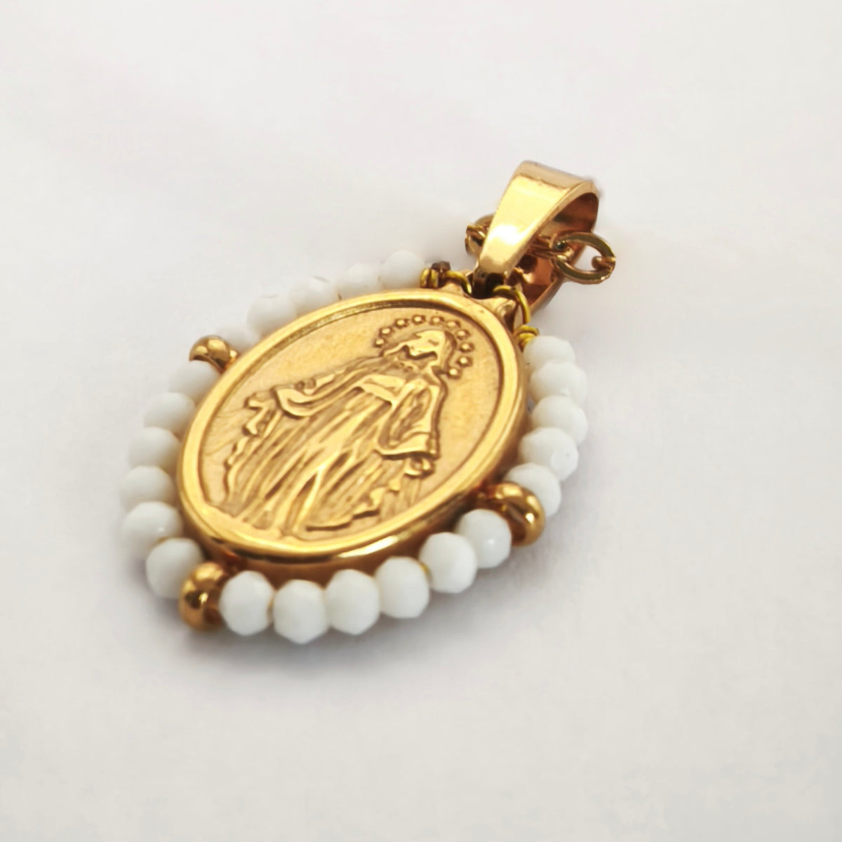 Pendente Orvalho dourado, com medalha de Nossa Senhora das Graças rodeada de contas brancas, em perspetiva.