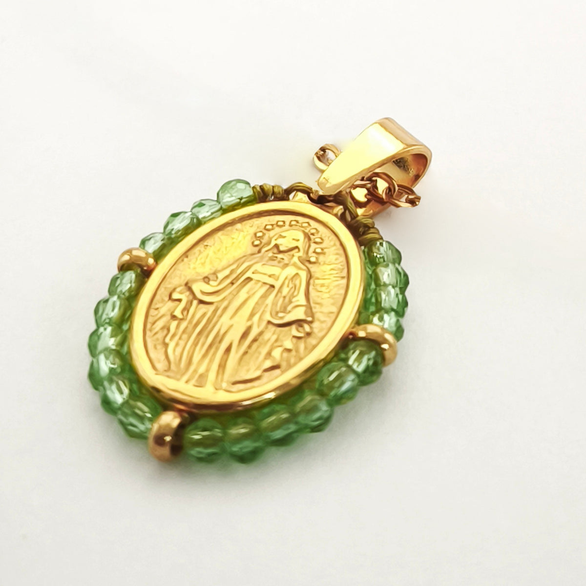 Pendente Orvalho dourado, com medalha de Nossa Senhora das Graças rodeada de contas verde-lima, em perspetiva.