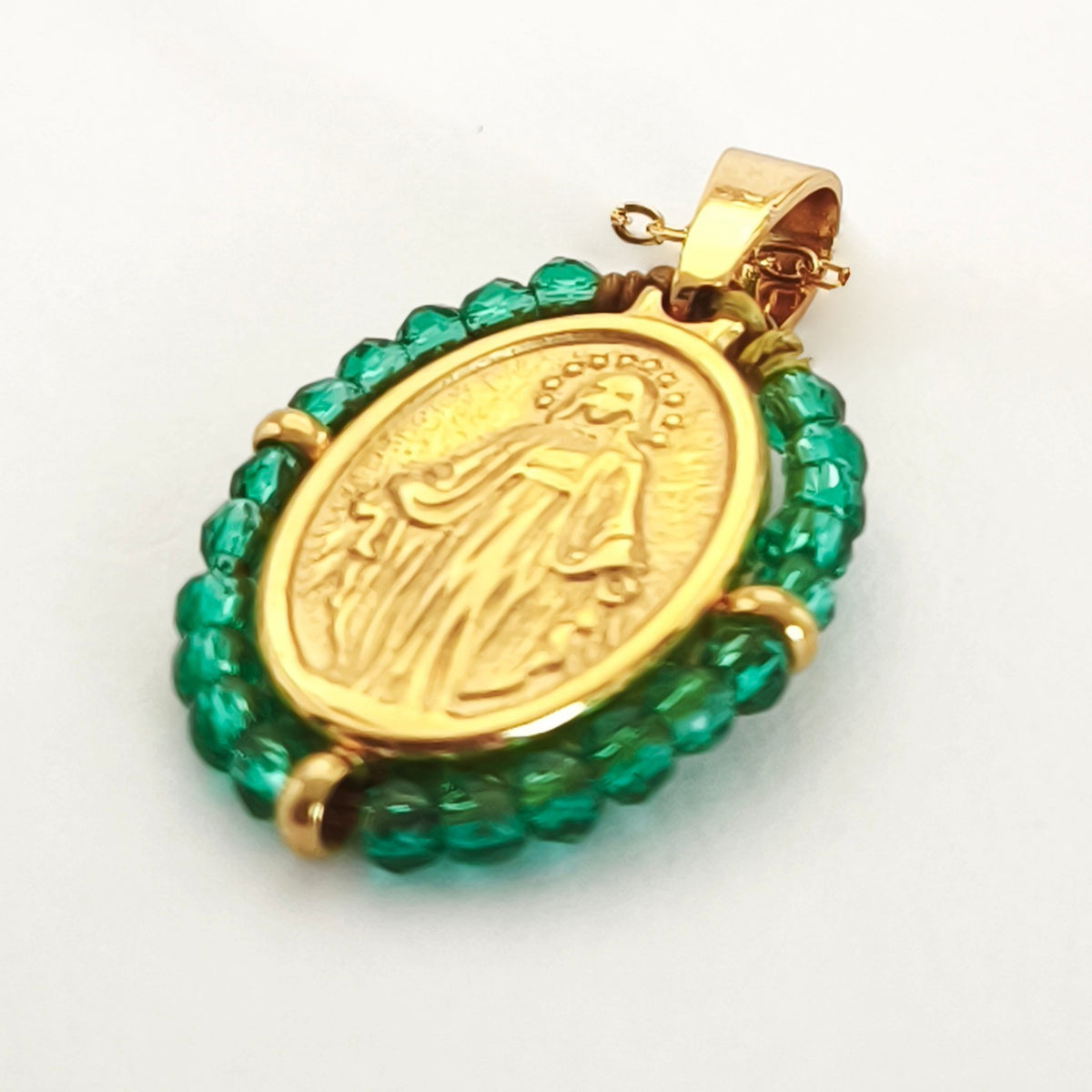 Pendente Orvalho dourado, com medalha de Nossa Senhora das Graças rodeada de contas verdes, em perspetiva.