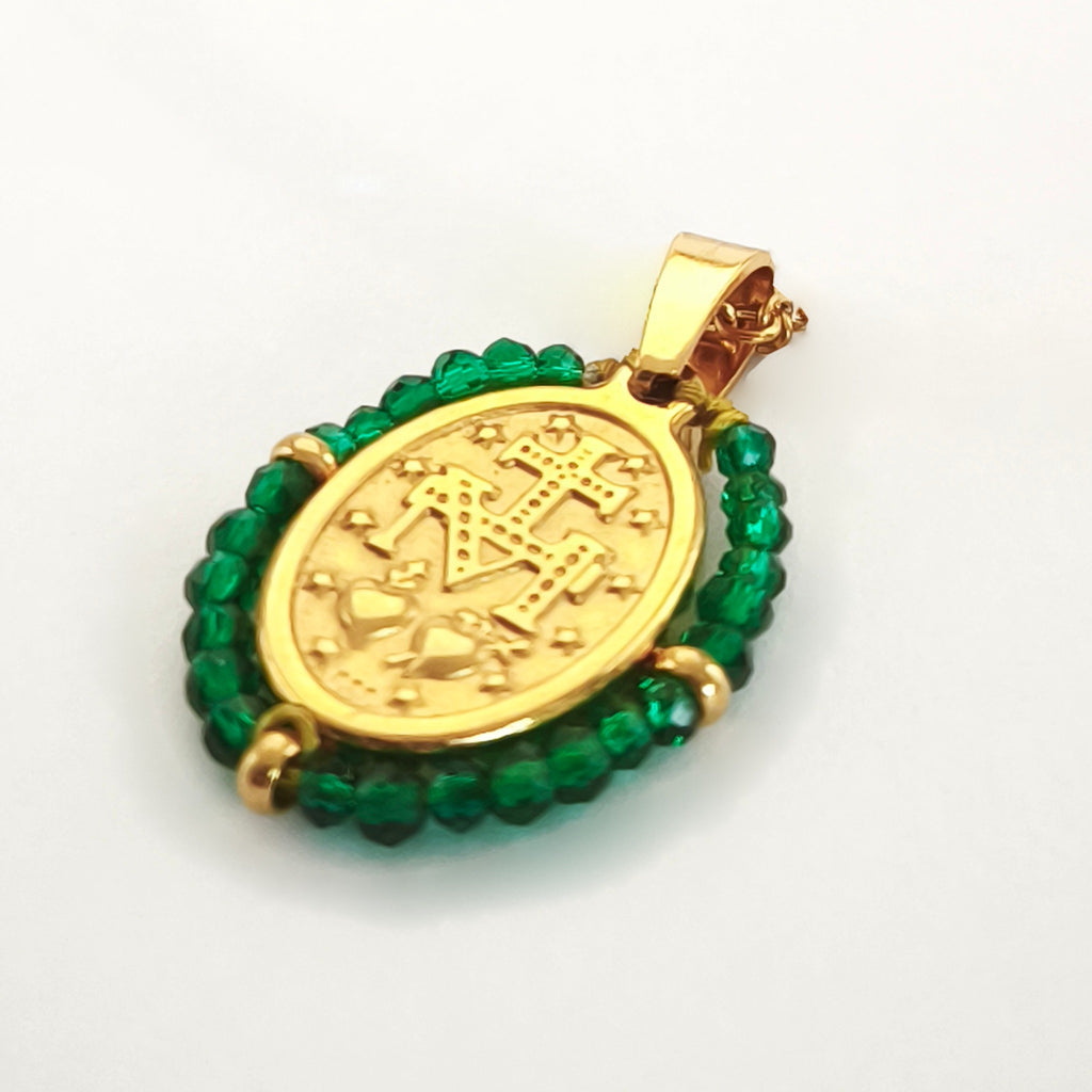 Pendente Orvalho dourado, verso da medalha rodeada de contas verde menta, com a letra M, a cruz, os dois corações e as doze estrelas.
