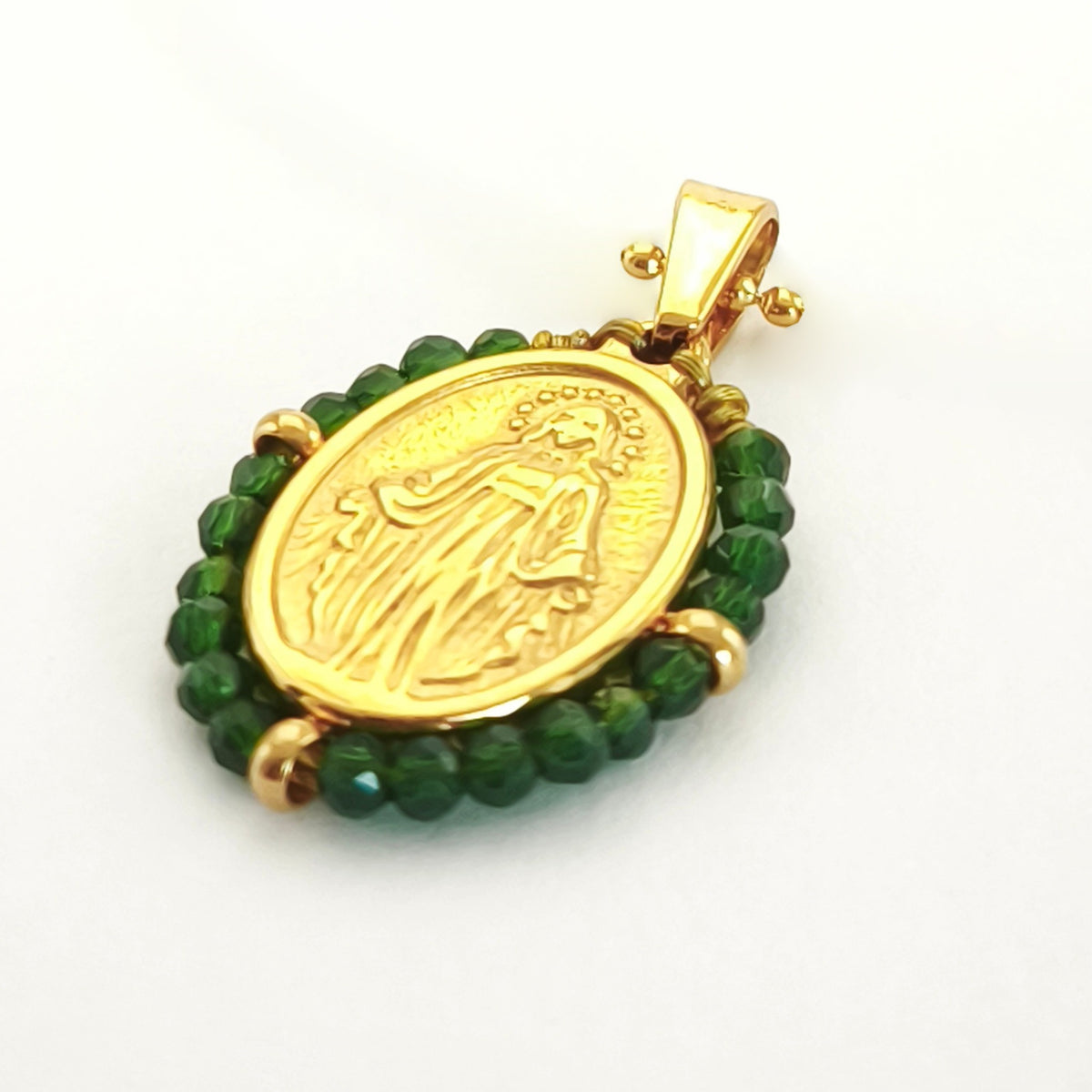 Pendente Orvalho dourado, com medalha de Nossa Senhora das Graças rodeada de contas verde escuro, em perspetiva.