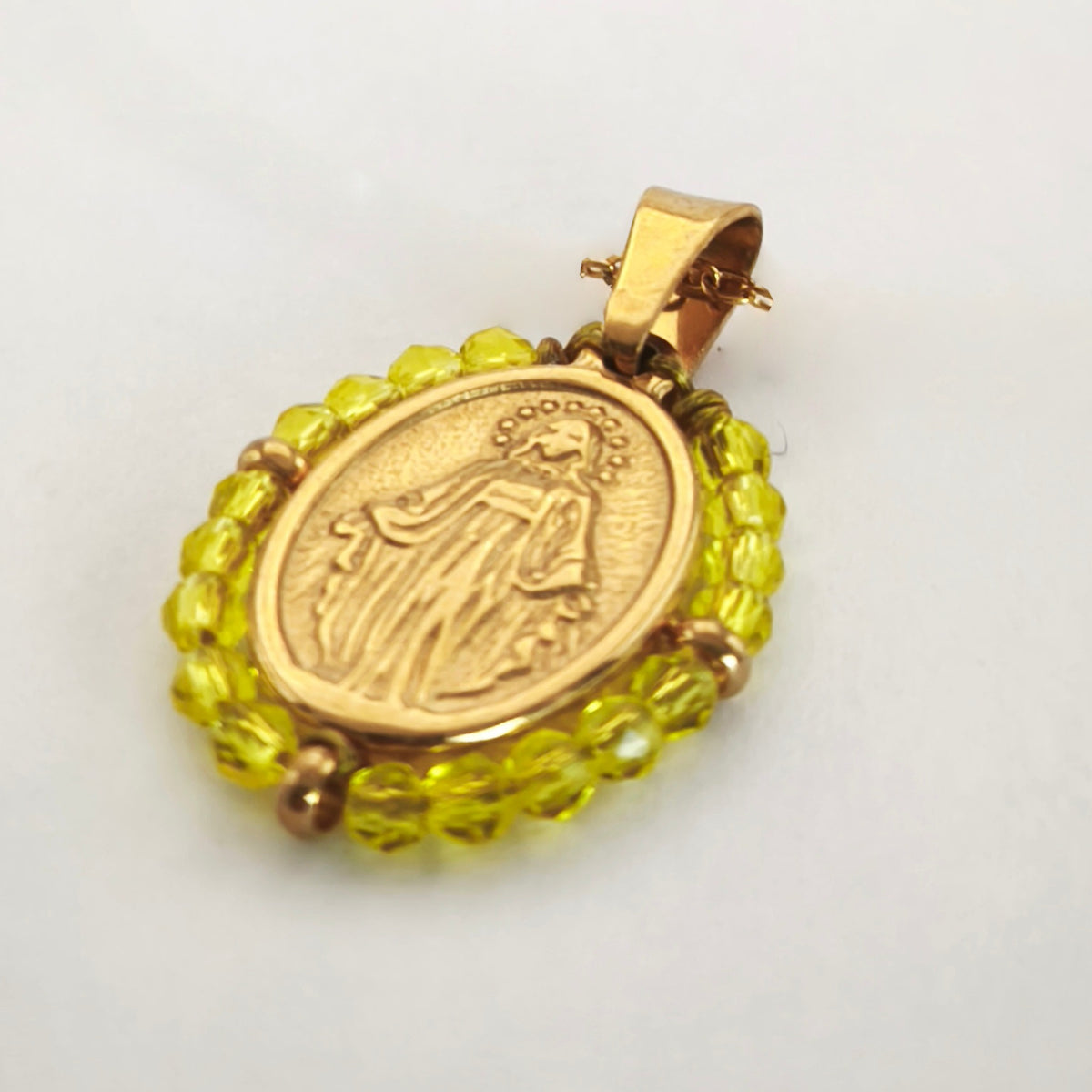 Pendente Orvalho dourado, com medalha de Nossa Senhora das Graças rodeada de contas amarelo limão, em perspetiva.