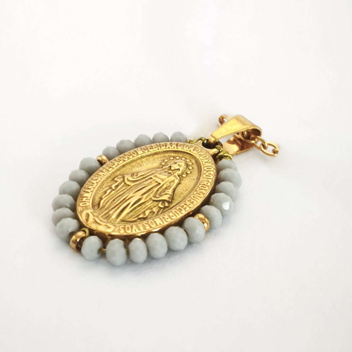 Pendente Auréola dourado, com medalha de Nossa Senhora das Graças rodeada de contas cinza claro, em perspetiva.