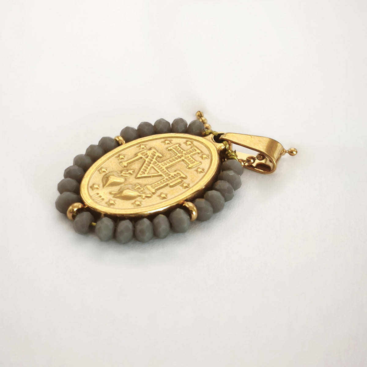 Pendente Auréola dourado, verso da medalha rodeada de contas cinza, com a letra M, a cruz, os dois corações e as doze estrelas.