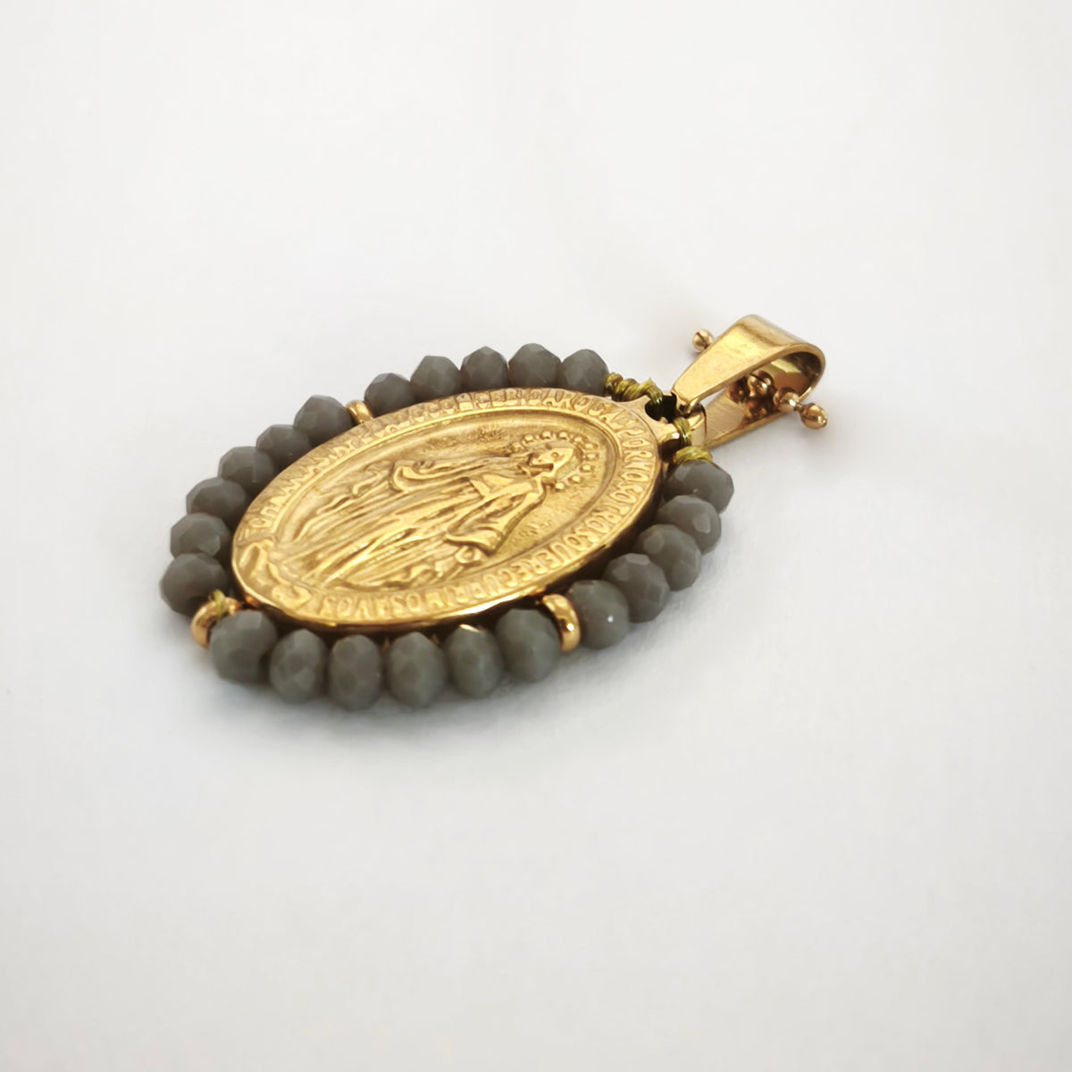 Pendente Auréola dourado, com medalha de Nossa Senhora das Graças rodeada de contas cinza, em perspetiva.