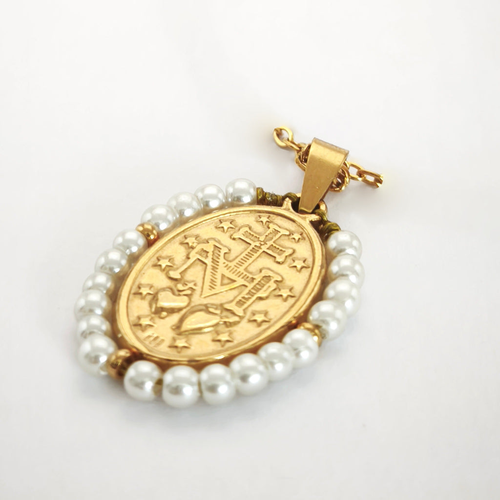 Pendente Auréola dourado, verso da medalha rodeada de pérolas artificiais, com a letra M, a cruz, os dois corações e as doze estrelas.