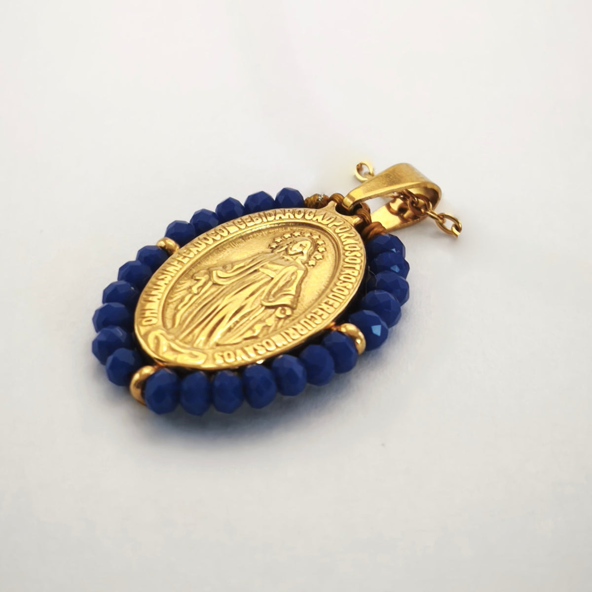 Pendente Auréola dourado, com medalha de Nossa Senhora das Graças rodeada de contas azul cobalto, em perspetiva.