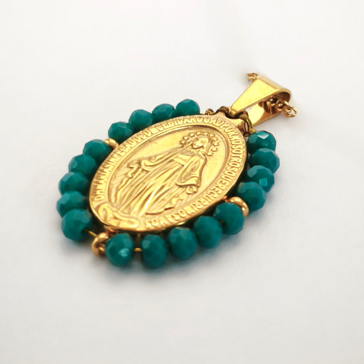 Pendente Auréola dourado, com medalha de Nossa Senhora das Graças rodeada de contas turquesa escuro, em perspetiva.