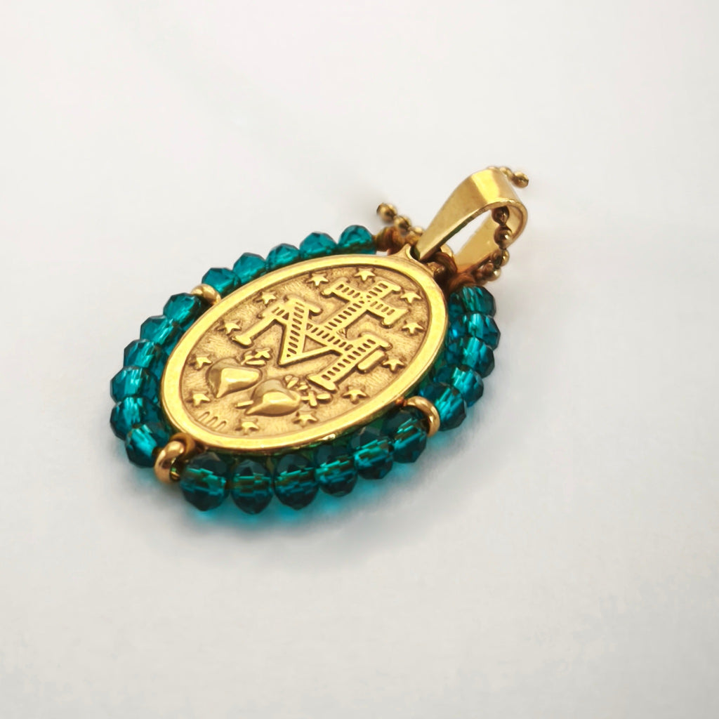 Pendente Auréola dourado, verso da medalha rodeada de contas petróleo, com a letra M, a cruz, os dois corações e as doze estrelas.