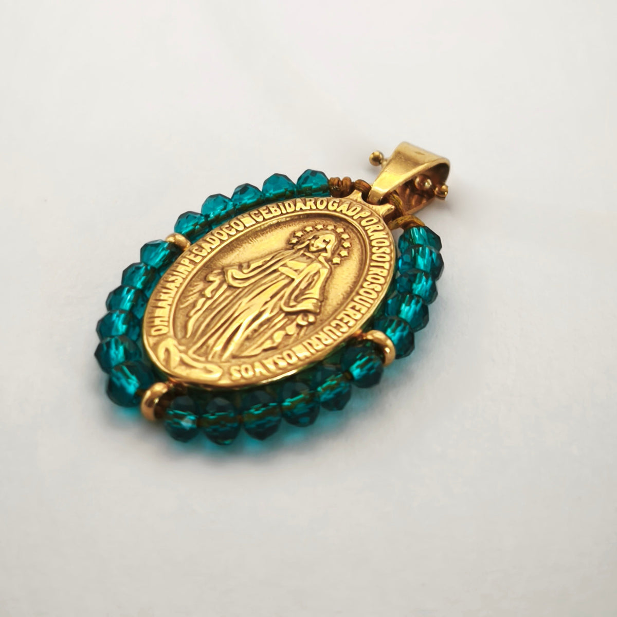 Pendente Auréola dourado, com medalha de Nossa Senhora das Graças rodeada de contas petróleo, em perspetiva.
