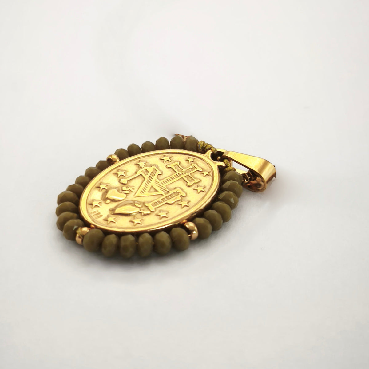 Pendente Auréola dourado, verso da medalha rodeada de contas caqui, com a letra M, a cruz, os dois corações e as doze estrelas.
