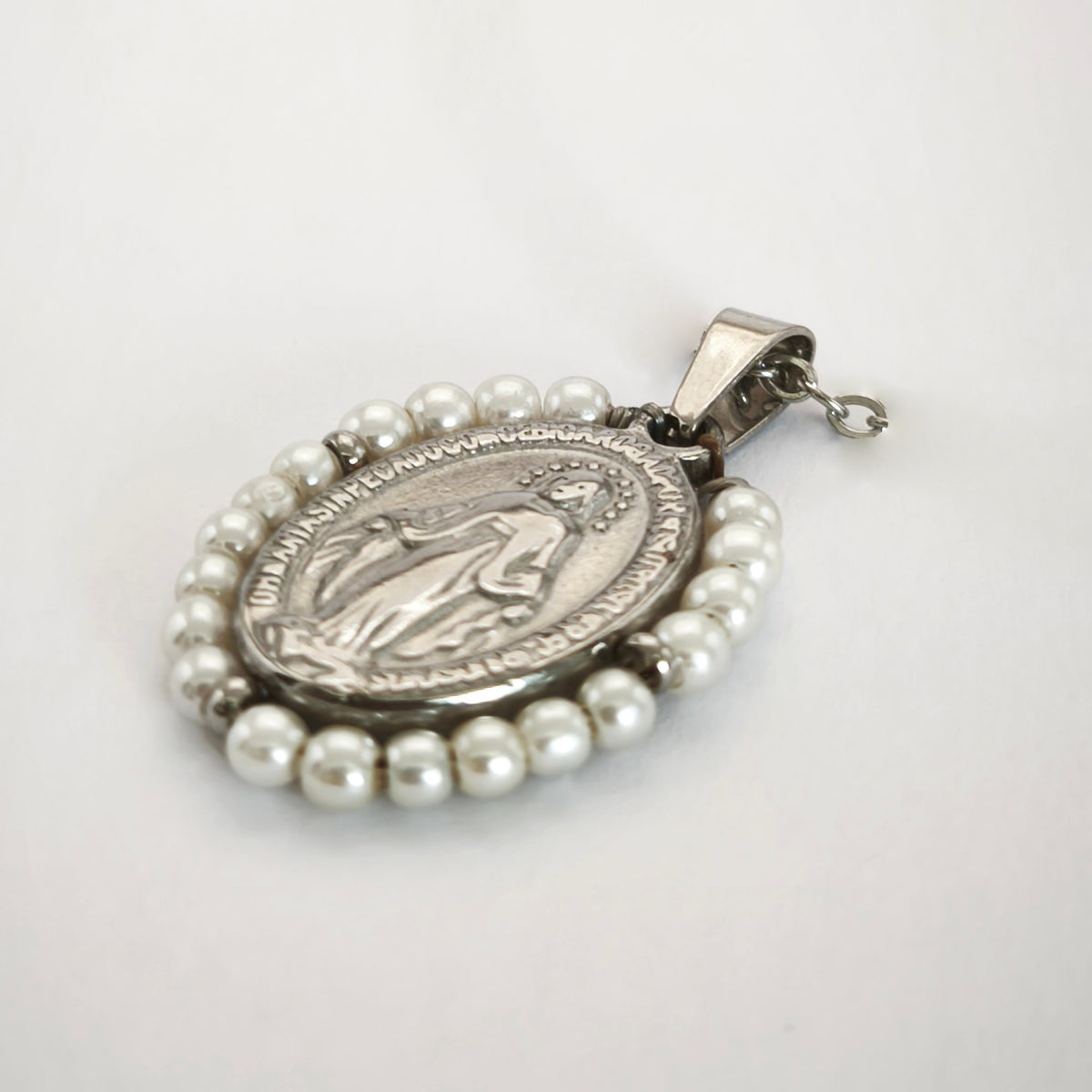 Pendente Auréola prateado, com medalha de Nossa Senhora das Graças rodeada de pérolas artificiais, em perspetiva.