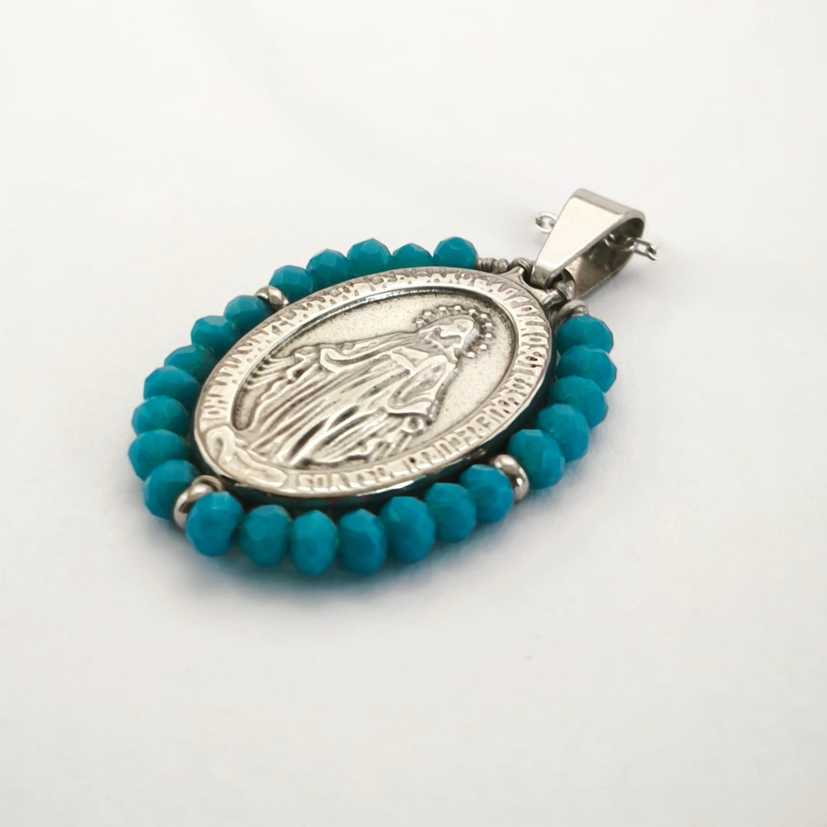 Pendente Auréola prateado, com medalha de Nossa Senhora das Graças rodeada de contas turquesa, em perspetiva.