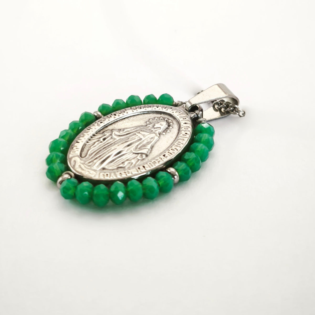 Pendente Auréola prateado, com medalha de Nossa Senhora das Graças rodeada de contas verdes, em perspetiva.