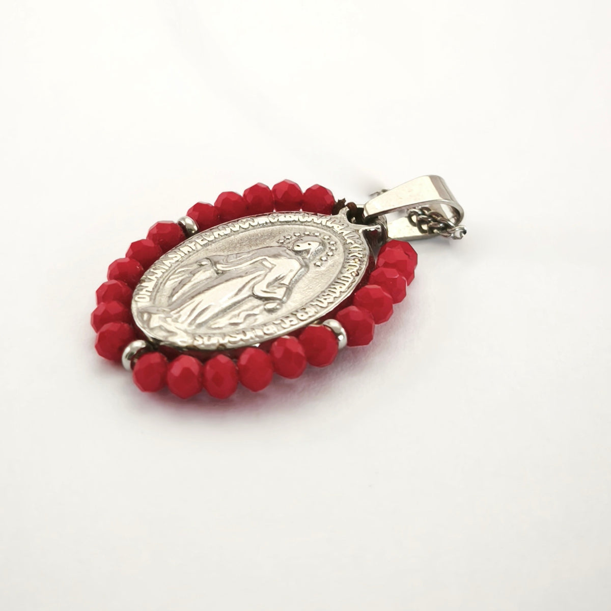 Pendente Auréola prateado, com medalha de Nossa Senhora das Graças rodeada de contas vermelhas, em perspetiva.
