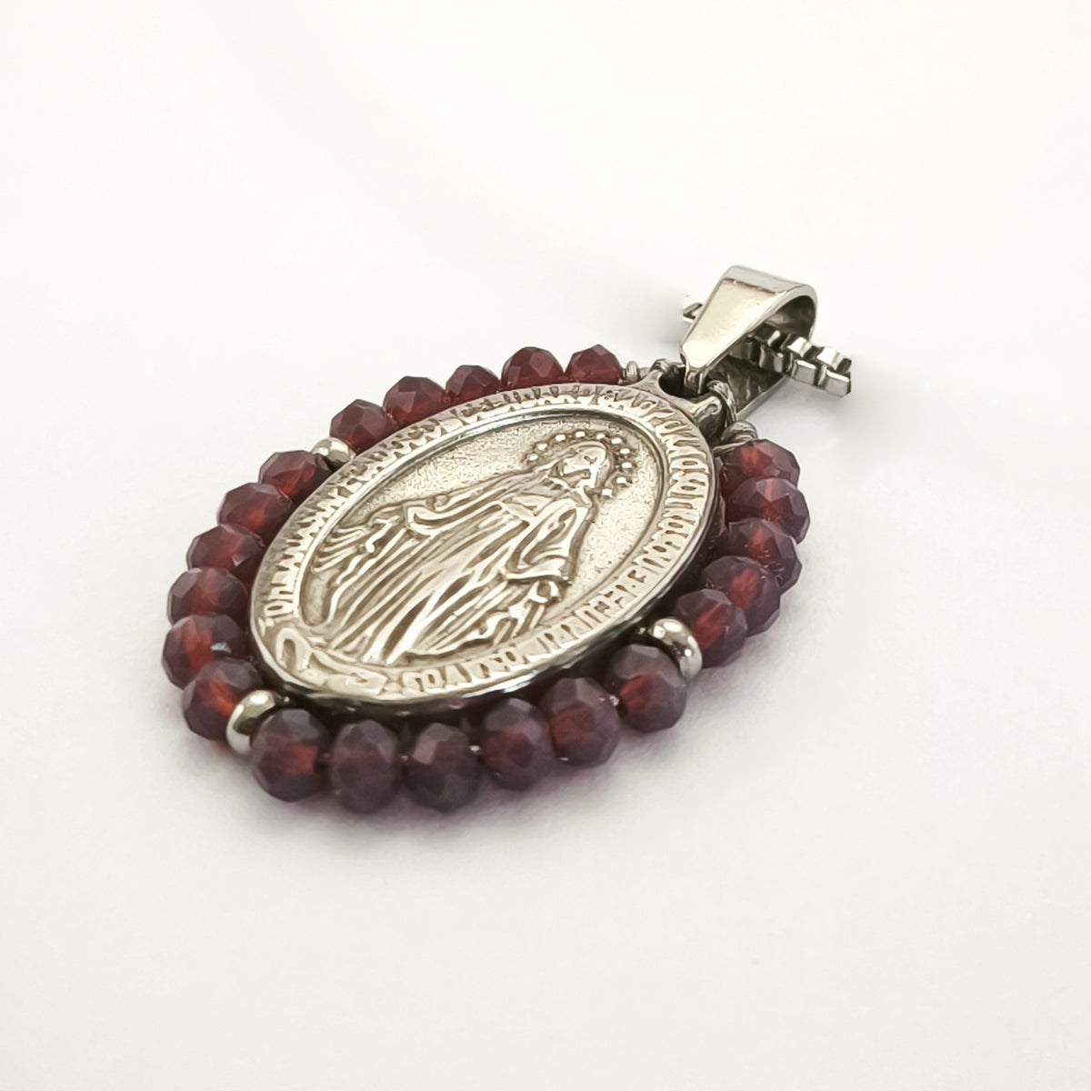 Pendente Auréola prateado, com medalha de Nossa Senhora das Graças rodeada de contas ameixa, em perspetiva.