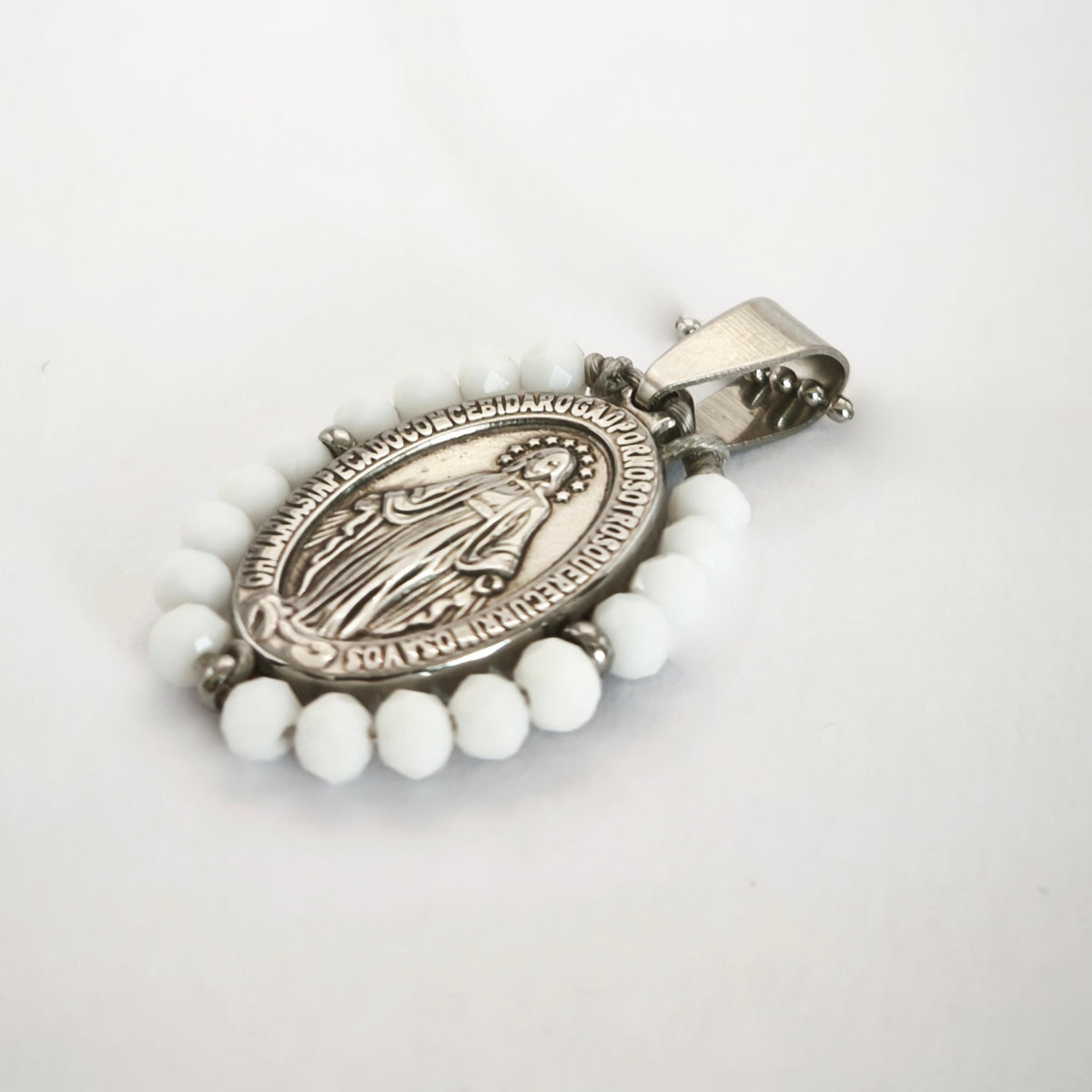 Pendente Auréola prateado, com medalha de Nossa Senhora das Graças rodeada de contas brancas, em perspetiva.