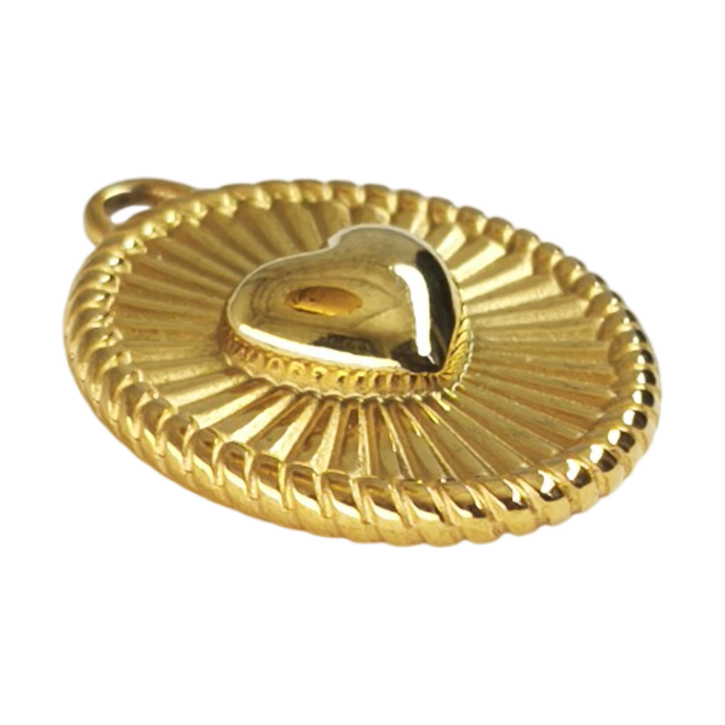 Pendente Compasso do Amor dourado em aço inoxidável, visto em ângulo, destacando o relevo do coração e o desenho radial, sobre fundo branco.